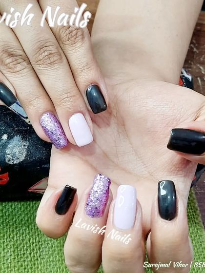 A cool, mixed-finish manicure on natural nails, combining black, white, and a sparkling purple glitter polish.