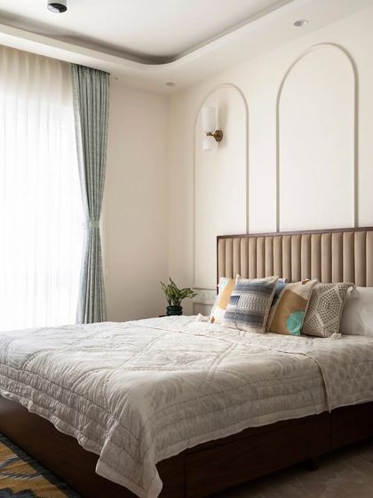 A full view of the master bedroom, showing the elegant false ceiling detail, the flowy curtains, and the overall sophisticated and restful atmosphere.