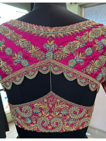 A unique back design on a magenta bridal blouse. The scalloped edges and intricate floral embroidery create a stunning visual, showcasing the possibilities of custom blouse design.