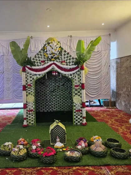 A simple and sweet house-shaped structure made from banana leaves and flowers, perfect for a small home-based naming ceremony.