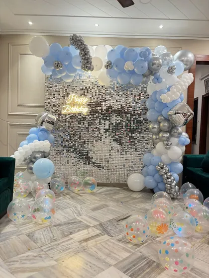 A full view of the cloud-themed shimmer wall decoration, showing the scattered transparent balloons on the floor.