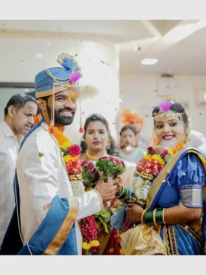 A candid shot of the couple during their wedding ceremony, showered with blessings and flowers. The joy on their faces is unmistakable.
