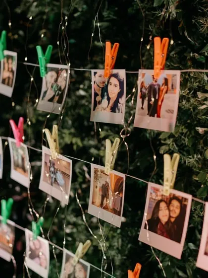 A personalized photo wall with polaroids of the couple's journey, clipped to strings of fairy lights. It's a sweet and interactive detail for guests to enjoy.