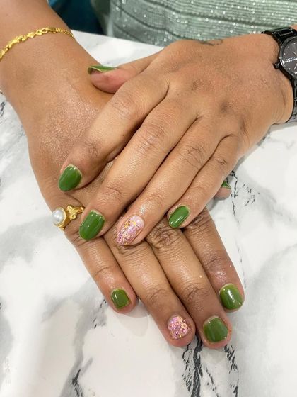 A simple and pretty design with green nails and a single accent nail with a pink floral pattern.