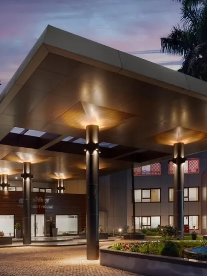 A twilight view of the guest house entrance, highlighting the dramatic lighting design that makes the building glow after dark.