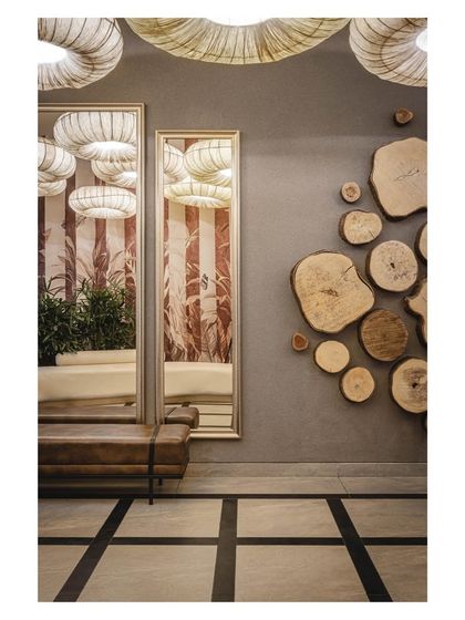 A detail of the entrance lobby, where a wall adorned with cross-sections of wood logs adds a rustic, natural texture. This contrasts with the sleek mirrors and modern lighting, showcasing our love for mixing materials.