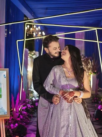 A tender moment during an engagement celebration. The groom holds his bride close as they share a loving look, surrounded by the vibrant colors of their event.