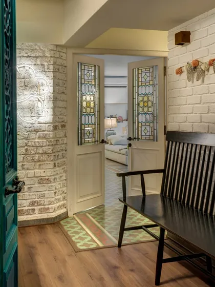 The entrance to Alia Bhatt's home sets a warm and inviting tone. The white brick wall, stained glass doors, and a simple bench create a feeling of comfort and ease, reflecting her desire for a home that was personal and unpretentious.