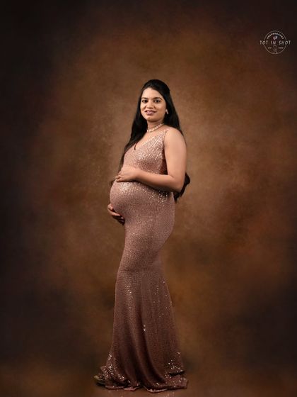 A classic profile shot of a mom-to-be in a shimmering rose-gold sequin gown, highlighting her beautiful baby bump.