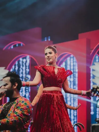 A moment from a high-energy sangeet performance. The bride takes center stage, surrounded by dancers with lotus-themed props, all part of our custom-designed, Vogue-inspired theme.