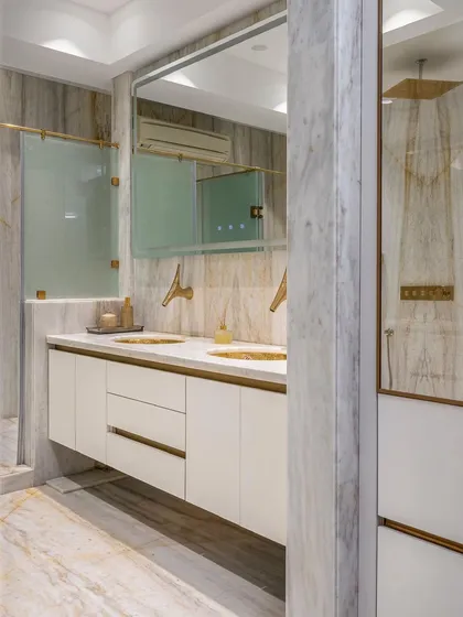 This view shows the master bathroom's well-considered layout, with a floating double vanity and a separate shower enclosure, all unified by the extensive use of white marble for a spa-like feel.