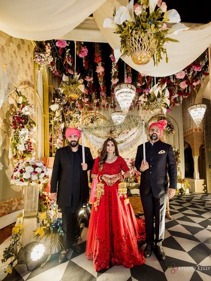 The bride's grand entrance, escorted by her brothers under a beautifully decorated floral canopy, a cherished moment in Indian weddings.