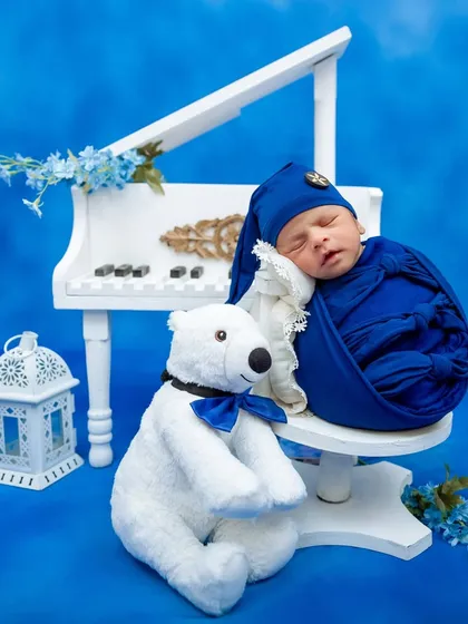 Another angle of the blue piano theme, showing the newborn swaddled and sleeping on the chair.