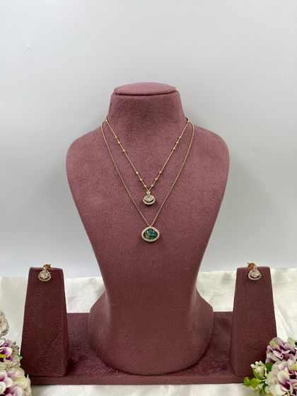 The Kritika Dual Shine Necklace Set. This delicate piece features two layered chains with unique, color-shifting stones, available in purple, green, and white.
