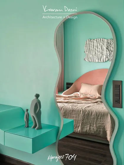 This custom wavy mirror in the daughter's room of Project 704 adds a playful, artistic touch. It reflects the bed and the unique wall art, making the room feel larger and more dynamic.
