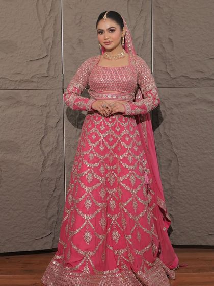 For the modern bride who loves pink. This full-sleeved rani pink lehenga with silver geometric embroidery is a chic and contemporary choice for a wedding ceremony or reception.
