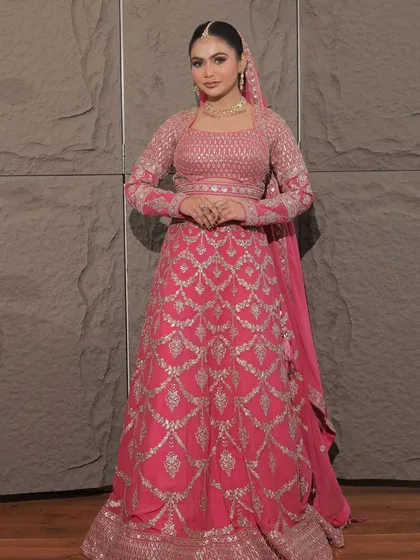 For the modern bride who loves pink. This full-sleeved rani pink lehenga with silver geometric embroidery is a chic and contemporary choice for a wedding ceremony or reception.