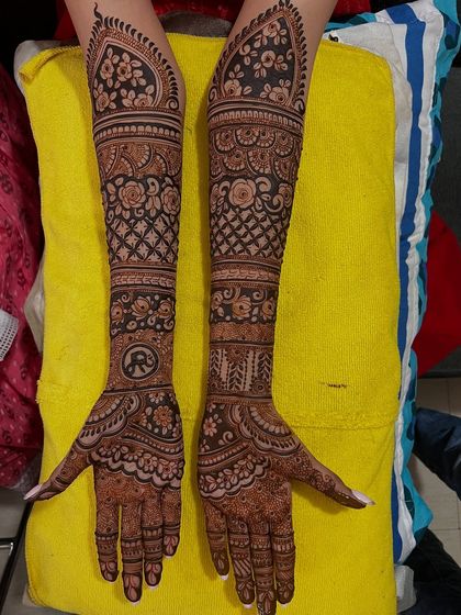 A lovely floral bridal design with a personalized initial 'R' on the palm. The combination of bold flowers and delicate net patterns creates a beautiful contrast.