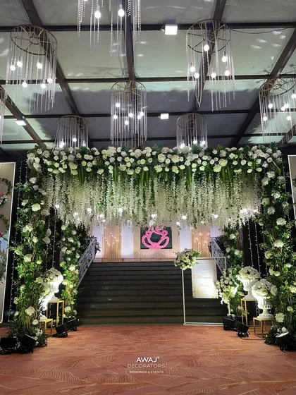 The view from the end of the entrance, looking back towards the stairs, showcasing the scale of the floral archway and chandeliers.