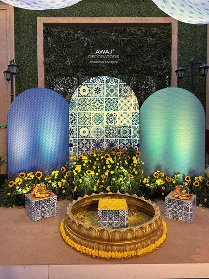 The central ritual area for the Haldi, featuring a traditional brass 'urli' surrounded by sunflowers and set against a Moroccan tile backdrop.