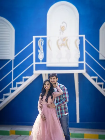 A lovely portrait of the couple against a vibrant blue wall at the Santorini-themed studio, capturing their happy smiles.