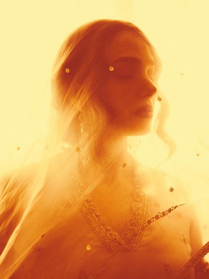 An abstract portrait for AR by Rhea Kapoor, using a sheer, sequined veil and a warm yellow filter to create a hazy, dreamlike effect.