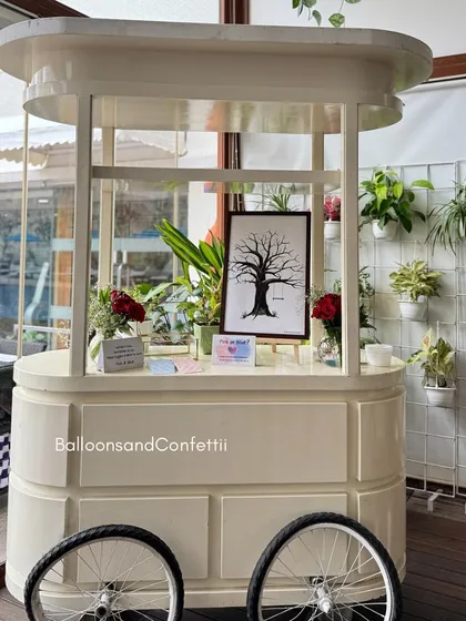 A charming white cart used as a station for guests to leave their thumbprint on a keepsake tree artwork for the baby.