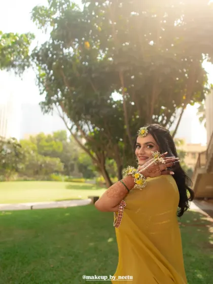 A beautiful outdoor shot of the Haldi bride. The sunlight highlights her glowing skin and the fresh, natural makeup look.