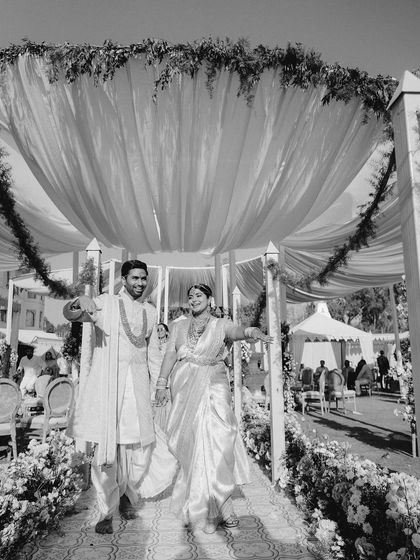 A timeless black and white shot of the couple's exit, highlighting the texture and form of the grand canopy and the lush greenery lining the structure.