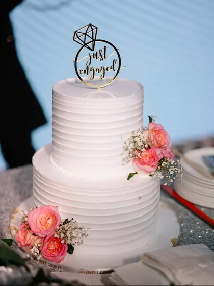 A close-up of the elegant "Just Engaged" cake. We coordinate with the best vendors to ensure every detail, no matter how small, is perfect.
