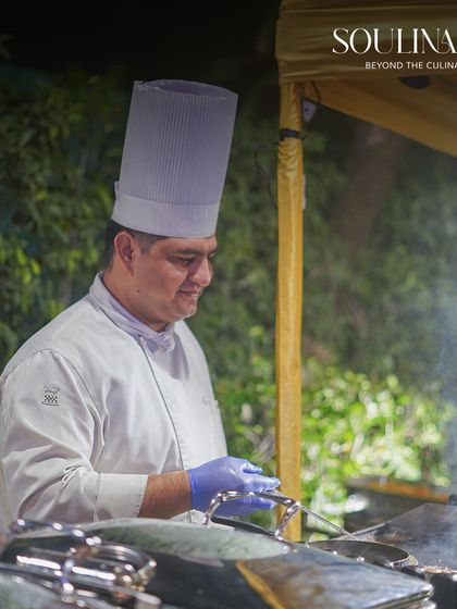 A chef grilling kebabs at an outdoor live station during a wedding celebration. The sight and aroma of freshly cooked food adds an irresistible energy to the event.