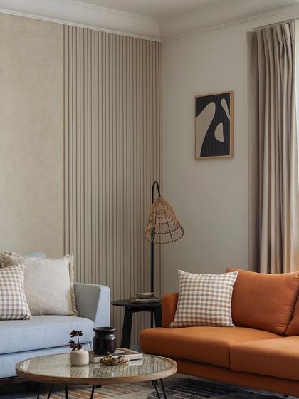 A close-up on the contrasting textures in the living room: the soft fabric of the sofas against the ribbed and smooth finishes of the feature wall.