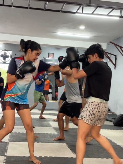 An action shot of two female boxers drilling. Our academy is a space where women can train seriously and develop their fighting skills.