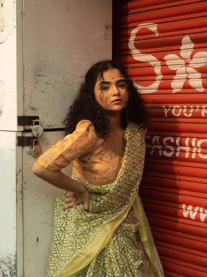 An editorial look featuring a traditional Indian bindi made of white dots and a graphic eyeliner. The hair is styled in natural, defined curls to complement the modern-ethnic vibe.