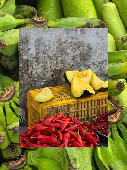 A creative collage with a background of green bananas, framing a shot of sliced pumpkin and red chillies.