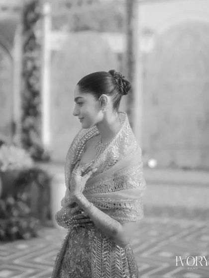 A classic black and white profile shot of the bride. This elegant portrait focuses on her beautiful updo, jewelry, and the graceful lines of her reception attire.