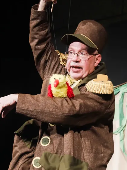 A close-up of the puppeteer from 'Penguin in my Pocket' operating a bird marionette. His costume adds to the theatricality of the performance.