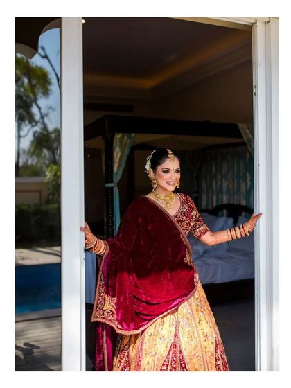 A beautiful bride in a rich velvet lehenga, ready for her Jaipur destination wedding. This shot captures her looking out of her palace hotel room, full of grace.