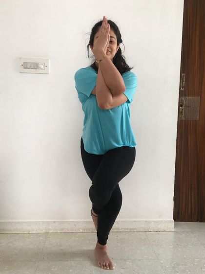 A smiling student enjoying the balance and focus required for Garudasana.