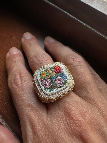 This statement ring captures a small, wild garden in micromosaic. Each tiny piece is hand-set to create a bouquet of roses, framed by an intricate 18k gold setting and a delicate diamond halo.