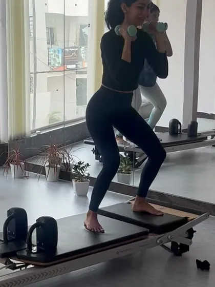 Performing squats with dumbbells on the reformer jumpboard adds a cardio element and challenges stability.