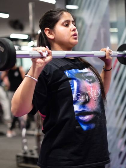 A member powers through a set of overhead presses with a barbell, a key exercise for developing strong shoulders.