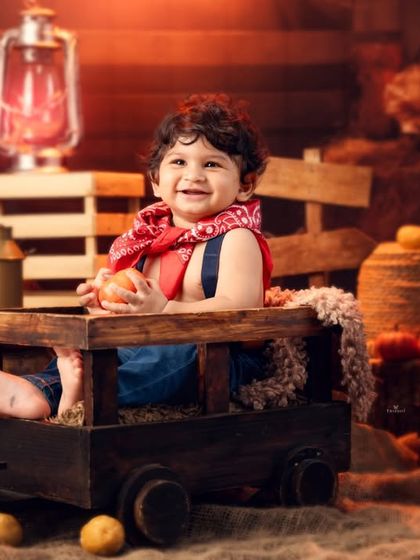 A full, happy smile from the little cowboy in his wooden cart, surrounded by a cozy, rustic atmosphere.