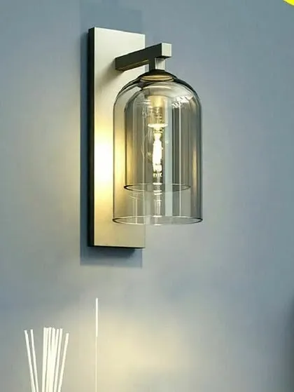 This ravishing retro wall lamp features a clear glass bell jar shade and an antique brass finish. The design is a perfect blend of vintage and modern styles, adding a touch of timeless elegance to any room.