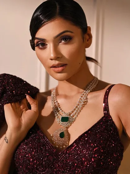 A close-up of the sequined burgundy lehenga look, focusing on the intricate diamond and emerald necklace. This highlights how our lighting is perfect for jewelry photography.
