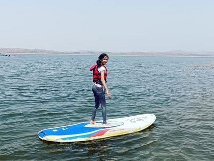 A smiling participant confidently balances on her paddleboard during our aqua sports camp.