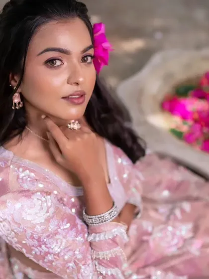 A model showcasing a glamorous look with a pink lehenga, perfect for a reception or sangeet. The makeup is subtle yet striking.