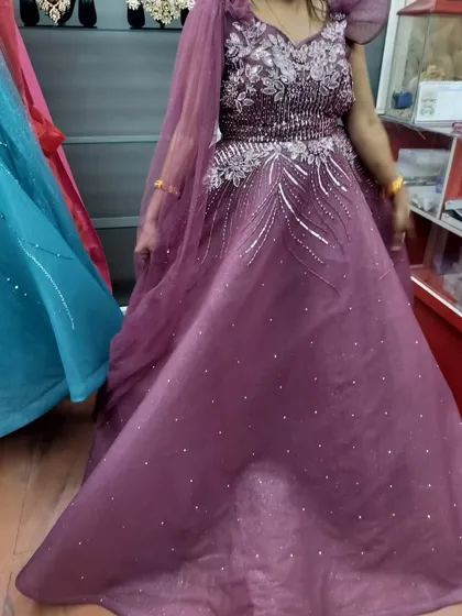 A lovely mauve gown with delicate silver embroidery and cape sleeves. This is a soft and romantic color choice for any special occasion.