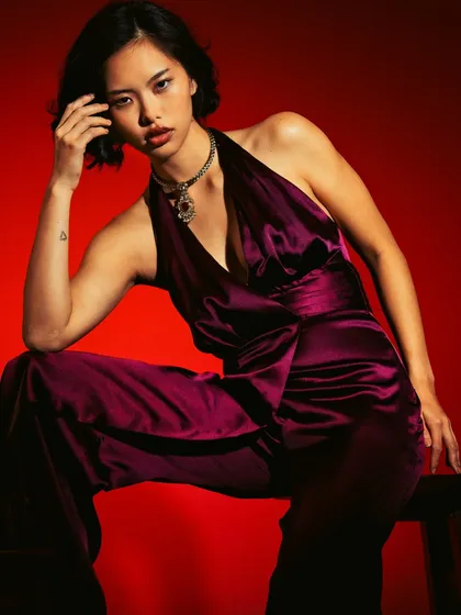A bold and intense portrait achieved with dramatic lighting. The strong contrast between the deep red background and the focused light on the model creates a powerful, moody atmosphere that we learn to control in the studio.