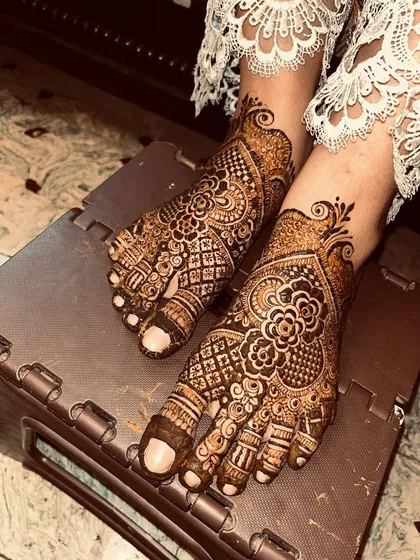 A crossed-feet pose showing the beautiful flow of the design. This is a classic choice for bridal feet mehendi.